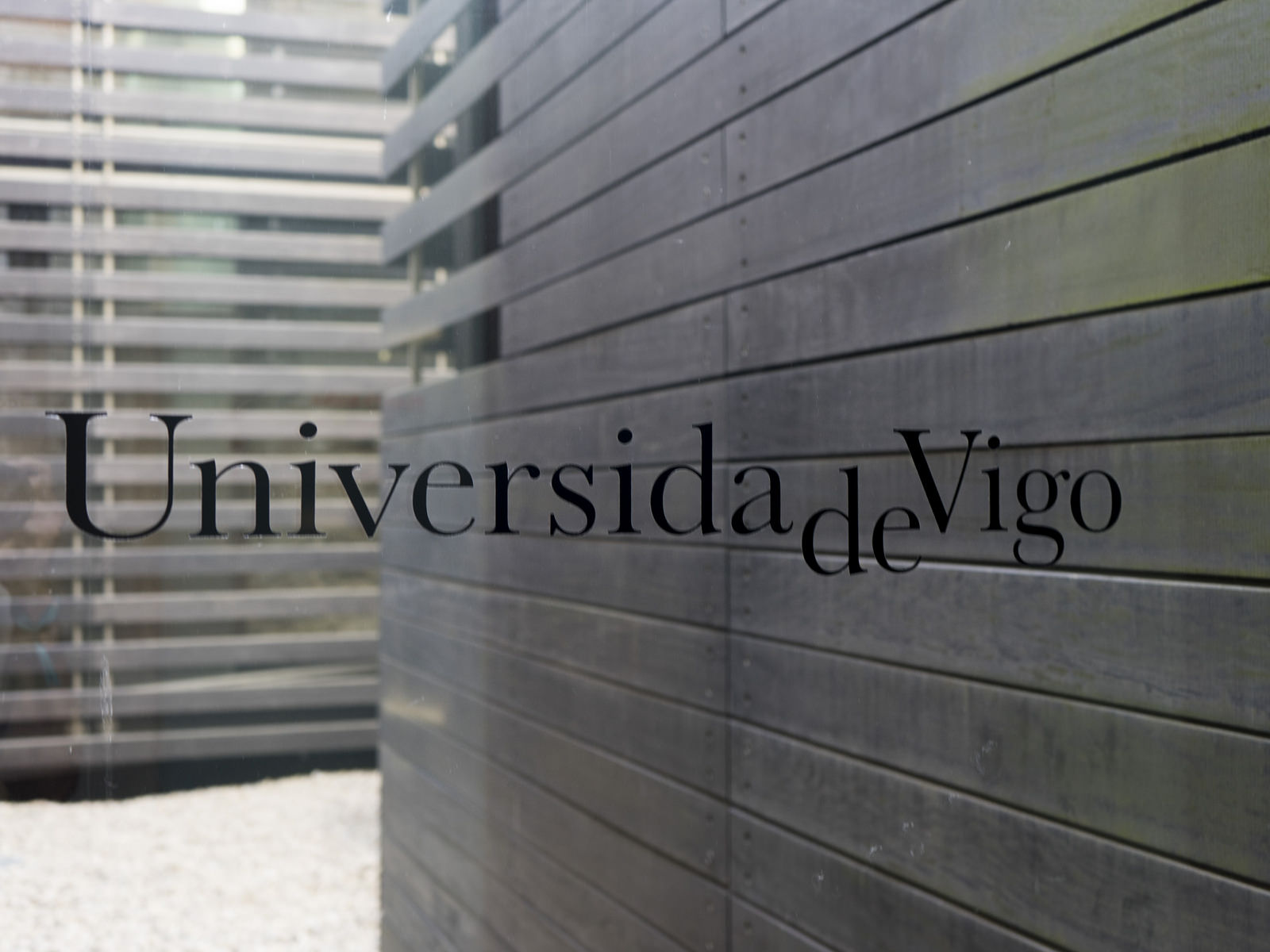 Cristal a una terraza donde se lee Universidade de Vigo