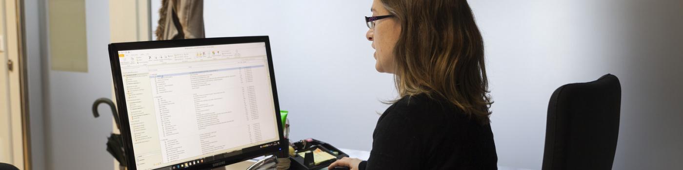 Unha traballadora da Universidade de Vigo sentada fronte ao seu ordenador