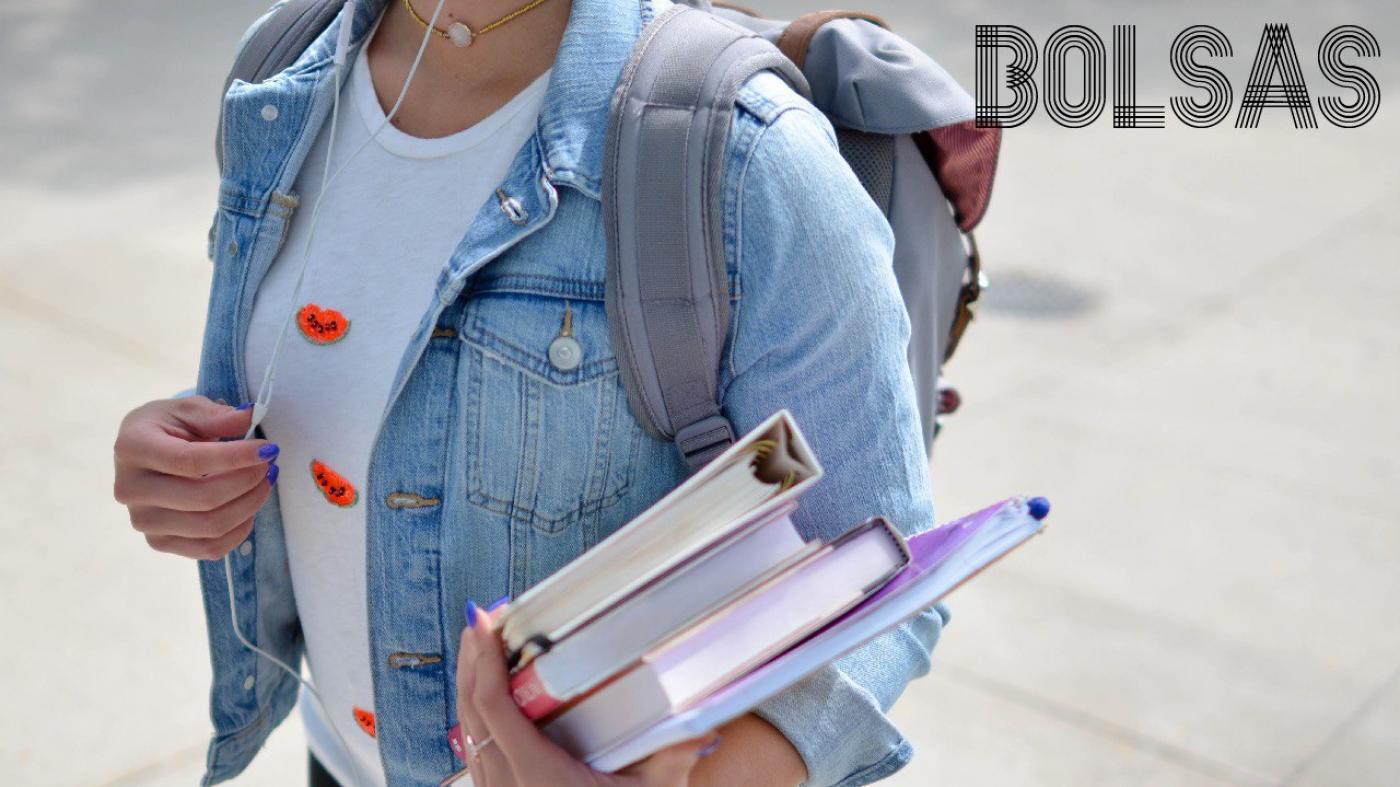 Imaxe dunha rapaza con libros debaixo do brazo e unha mochila