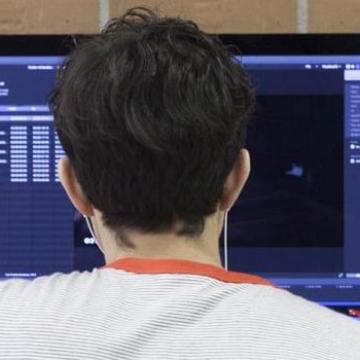 Imaxe dun rapaz de costas diante dun ordenador