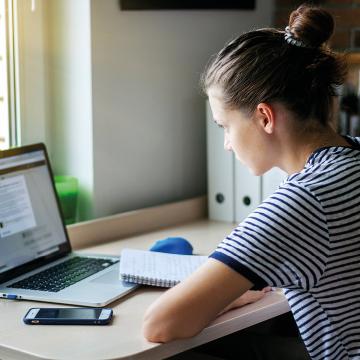 Imaxe dunha rapaza traballando cun portátil para difundir a información sobre a teledocencia